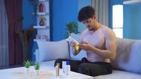 Young-man-tired-at-night-at-home-applying-cream-and-massaging-his-painful-areas.